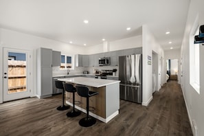 Una cocina moderna con una isla central, electrodomésticos de acero inoxidable y vistas al exterior.