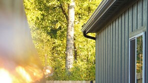 A pathway leading to a building with a wooden fence and a blue chair in the background. - New Cozy Modern Cottage with Hot Tub & Fire Pit! (Ponderay)