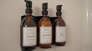 Trois flacons de produits de soins capillaires : un shampooing, un après-shampooing et un gel douche, chacun muni d’un distributeur à pompe.