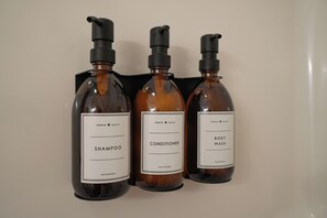 Three bottles of hair care products: shampoo, conditioner, and body wash, each with a pump dispenser.