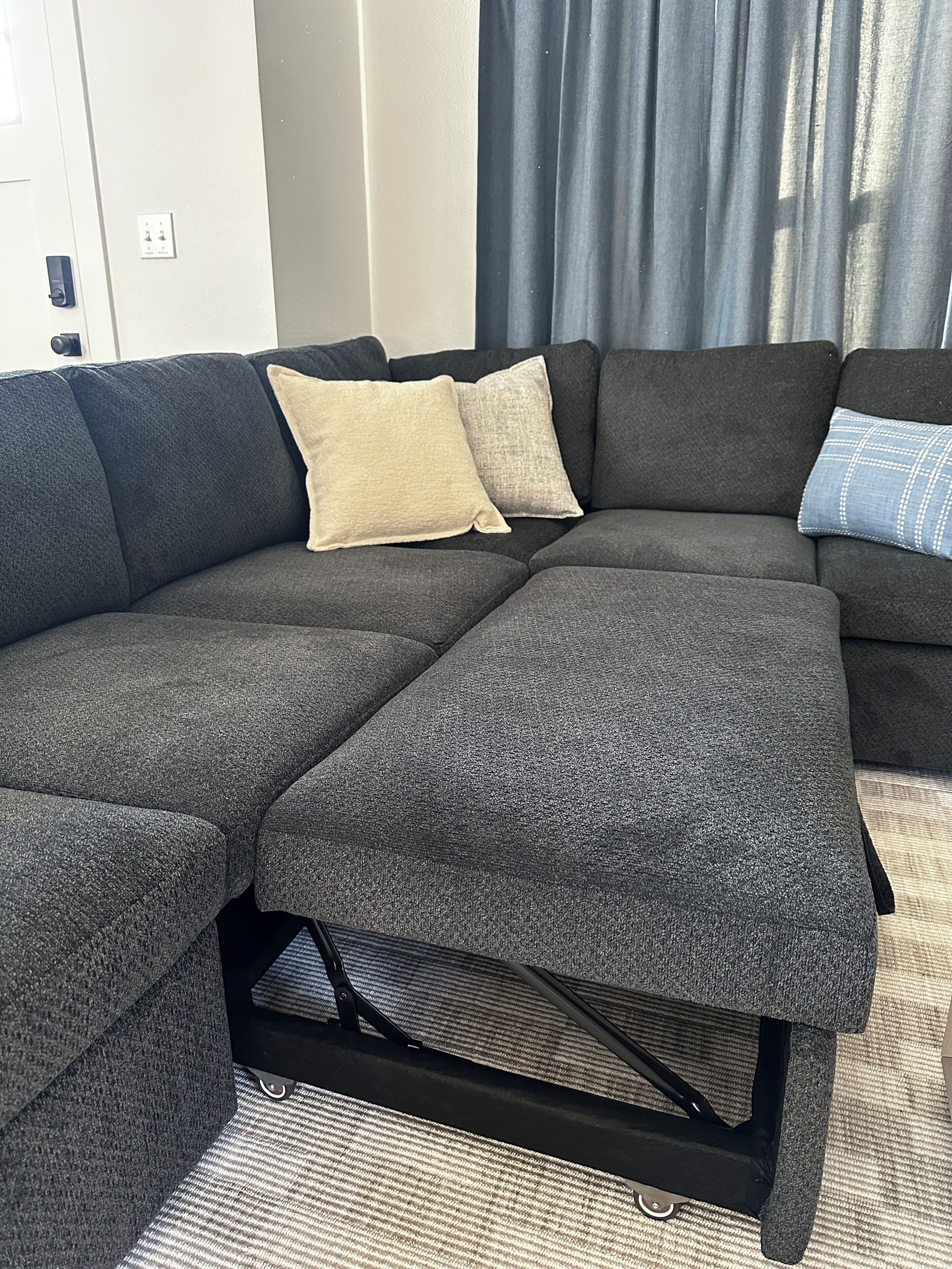 A sectional sofa with a dark fabric, two pillows, and a black metal frame.