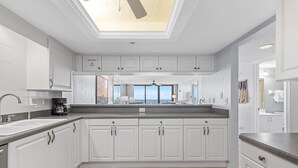 Een moderne keuken met witte kasten, een dakraam en uitzicht op de stad.