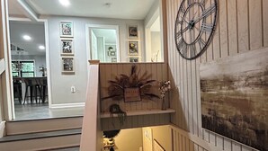 A staircase with a chevron-patterned rug leading to a lower level. A clock and decorative wall art are visible on the upper landing. - Escape to North Georgia.. near wineries, hiking, and river adventures. (Dahlonega)