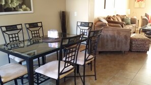 Un área de comedor con una mesa de vidrio y sillas, un sofá y un reposapiés estampado.