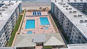 Un hôtel de grande hauteur doté de deux piscines, offrant une vue sur la plage et disposant d’un parking sur le toit.