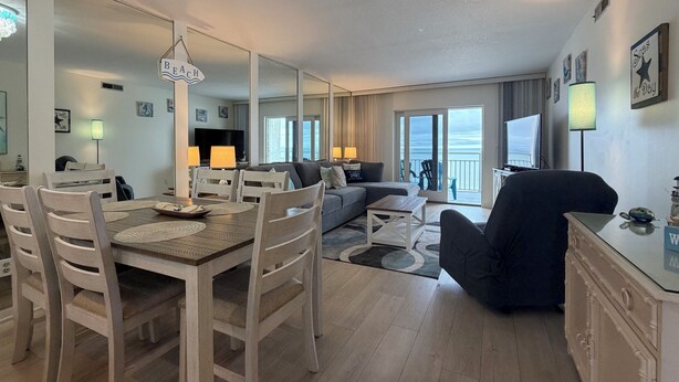 Un salon spacieux comprenant un coin repas, un canapé et un téléviseur. On y trouve également des chaises et une table avec des sets de table.
