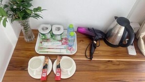 A wooden table with a tray of toiletries, a kettle, and a plant. - Vangvieng Victory Hostel (Vang Vieng)