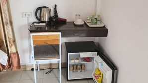 A compact room with a bed, a small desk with a kettle, a cup, and a tray with snacks. - Vangvieng Victory Hostel (Vang Vieng)