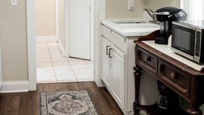 A kitchen with white cabinets, a microwave, and a coffee maker on a wooden countertop. - White House on Market (Hermann)