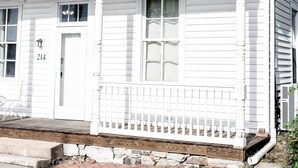 A white wooden house with a porch, a chimney, and a brick driveway. - White House on Market (Hermann)