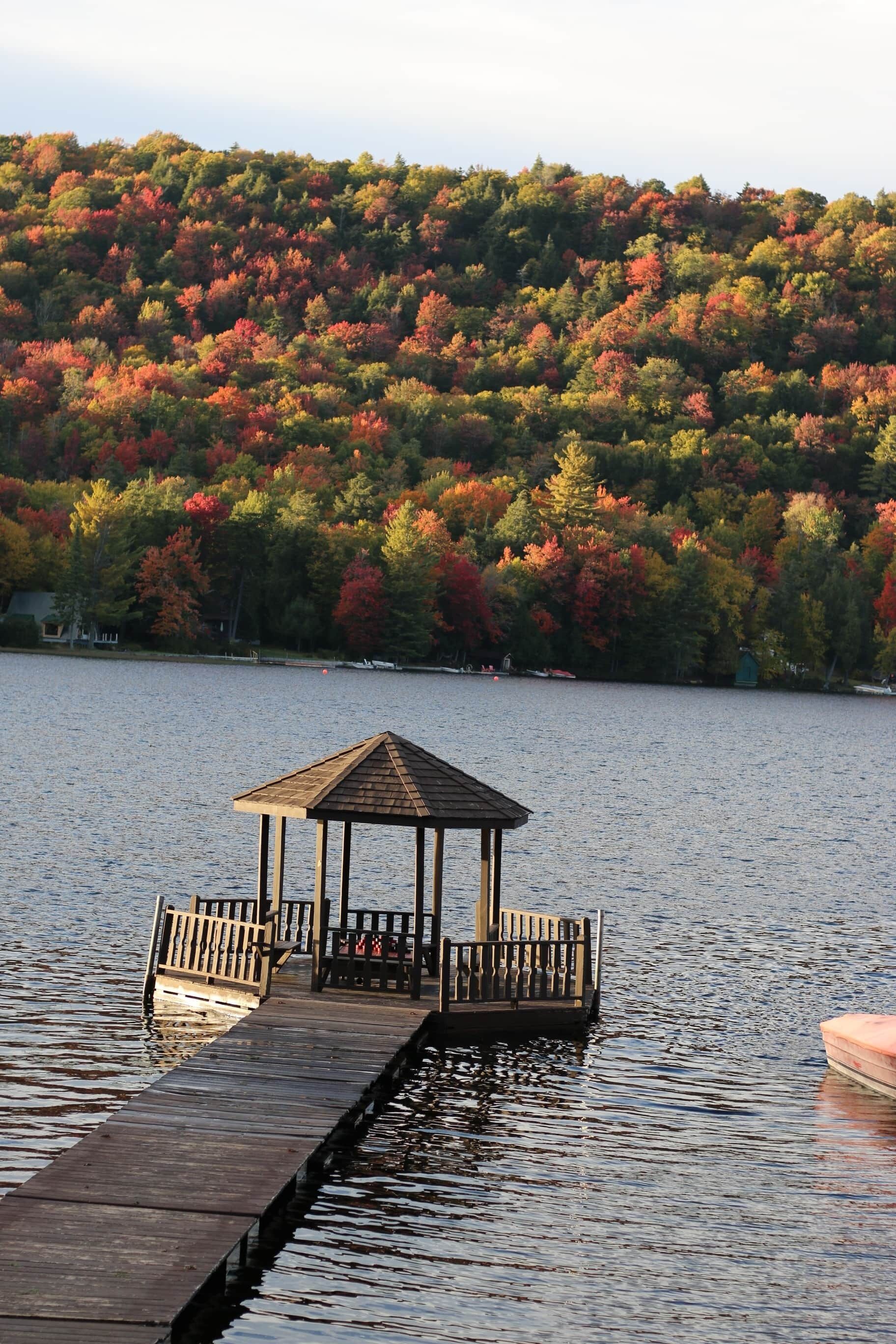 A wooden pier extending into a lake with a gazebo at the end.