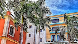A courtyard with palm trees, a stone archway, and a building with balconies.