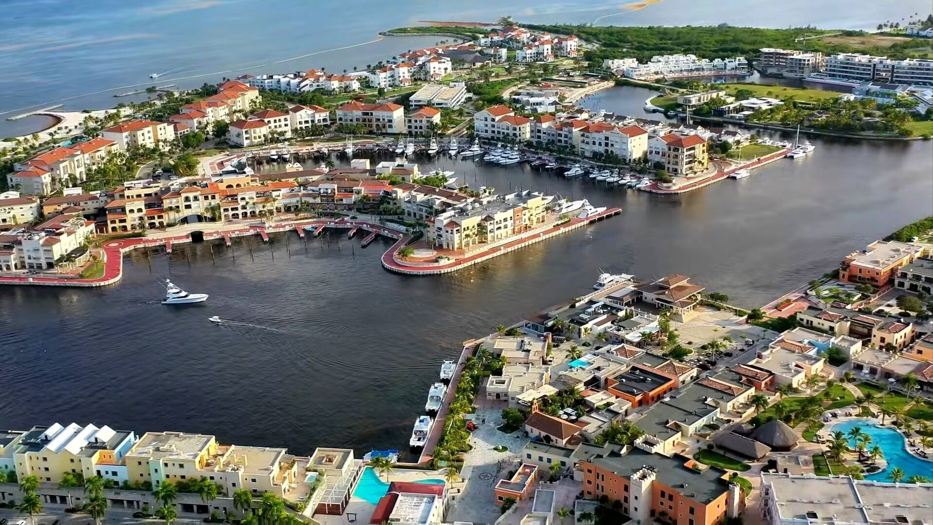 Vue aérienne d’une ville côtière avec un port de plaisance, des immeubles résidentiels et une piscine.