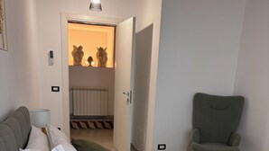 A bedroom with a large bed, a green armchair, and a door leading to another room.