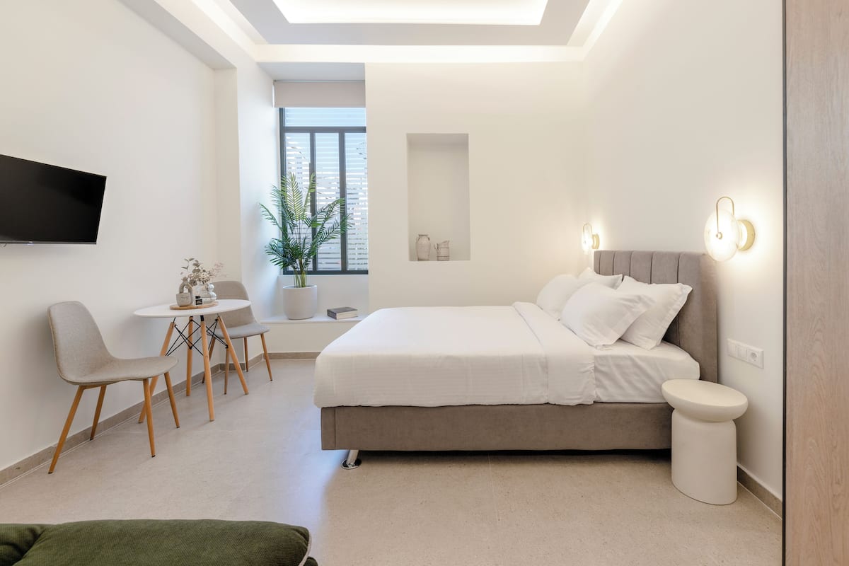 A modern bedroom with a bed, bedside table, and a small seating area with chairs.