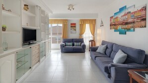 Una sala de estar con televisor, sofá y un cuadro en la pared.