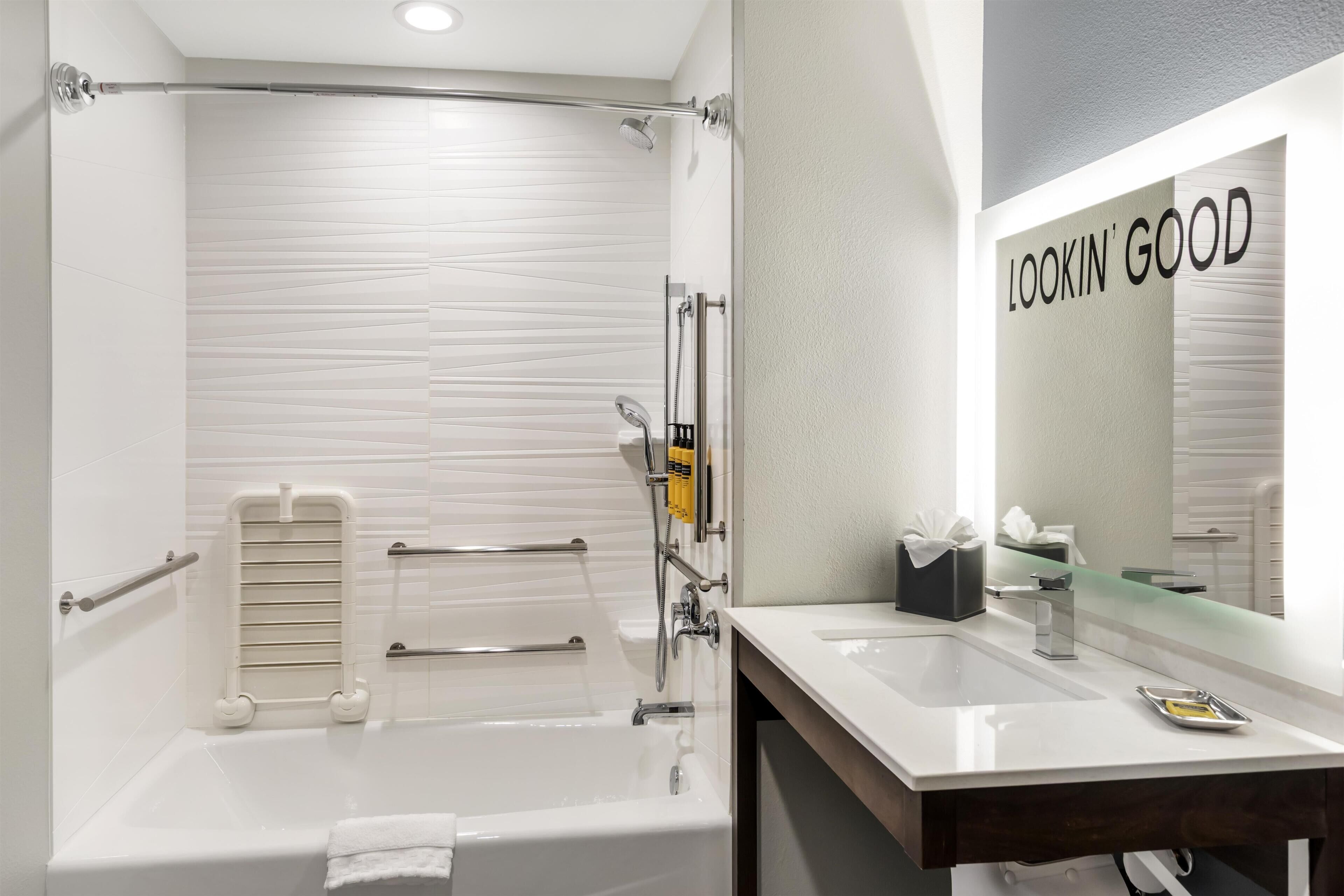 A modern bathroom with a bathtub, a shower, a vanity with a mirror, and a towel rack.