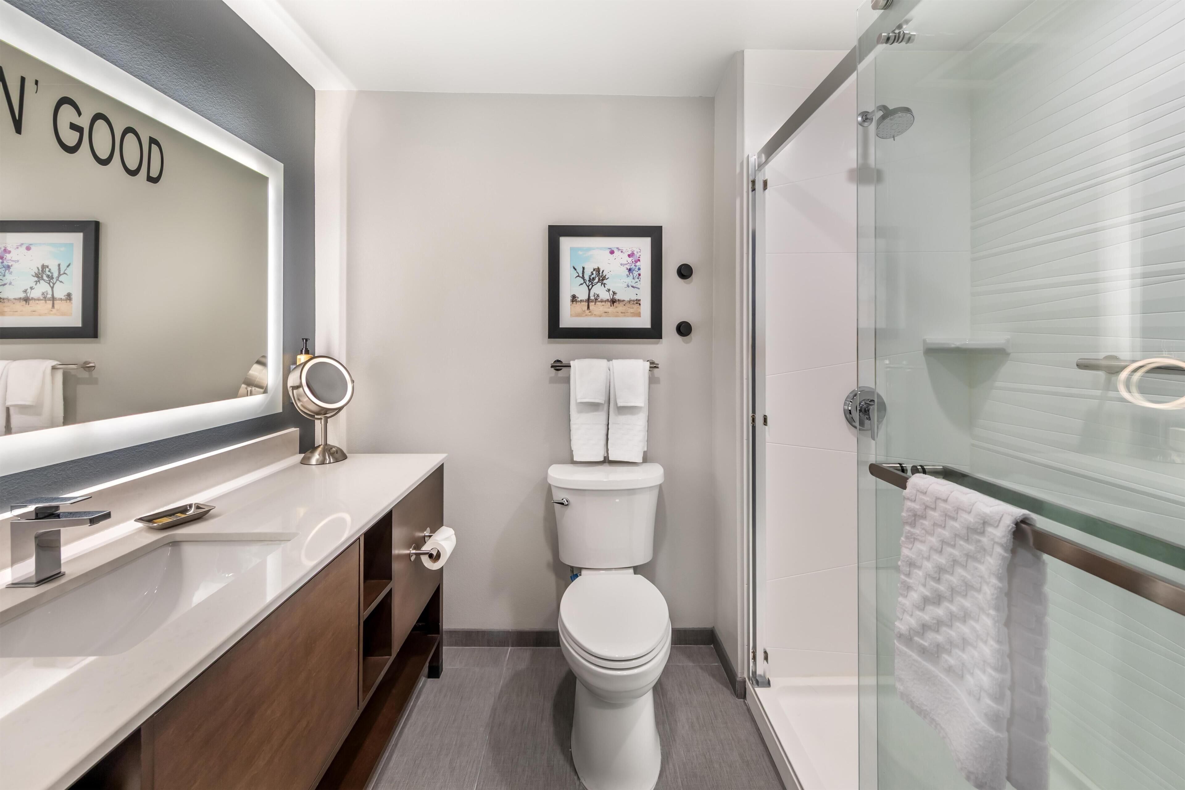 A modern bathroom with a toilet, sink, and glass shower enclosure.