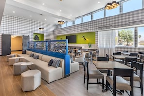 A modern lounge area with a sofa, round tables, and a seating area with chairs.