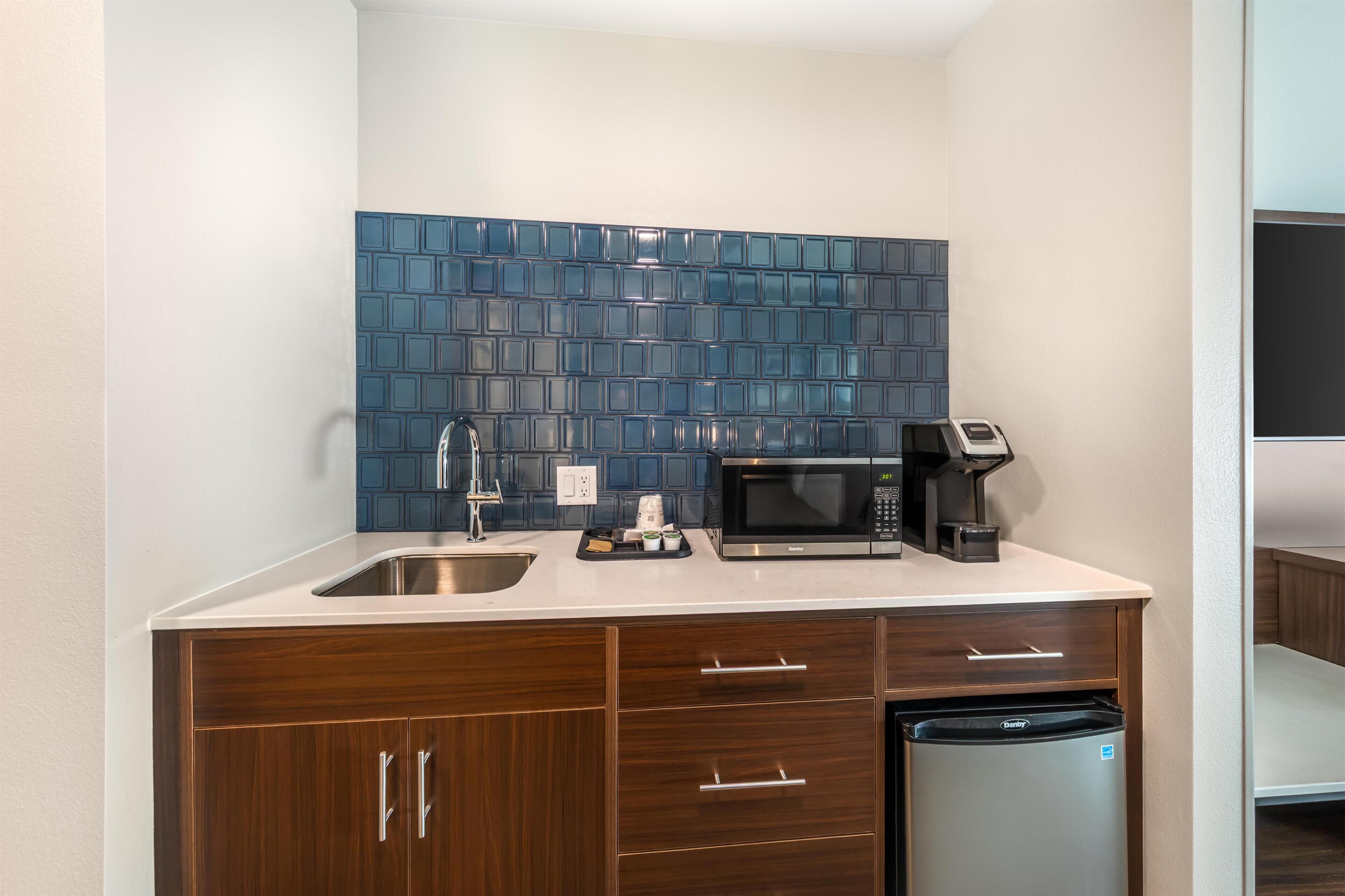 A compact kitchen with a sink, microwave, coffee maker, and dishwasher.