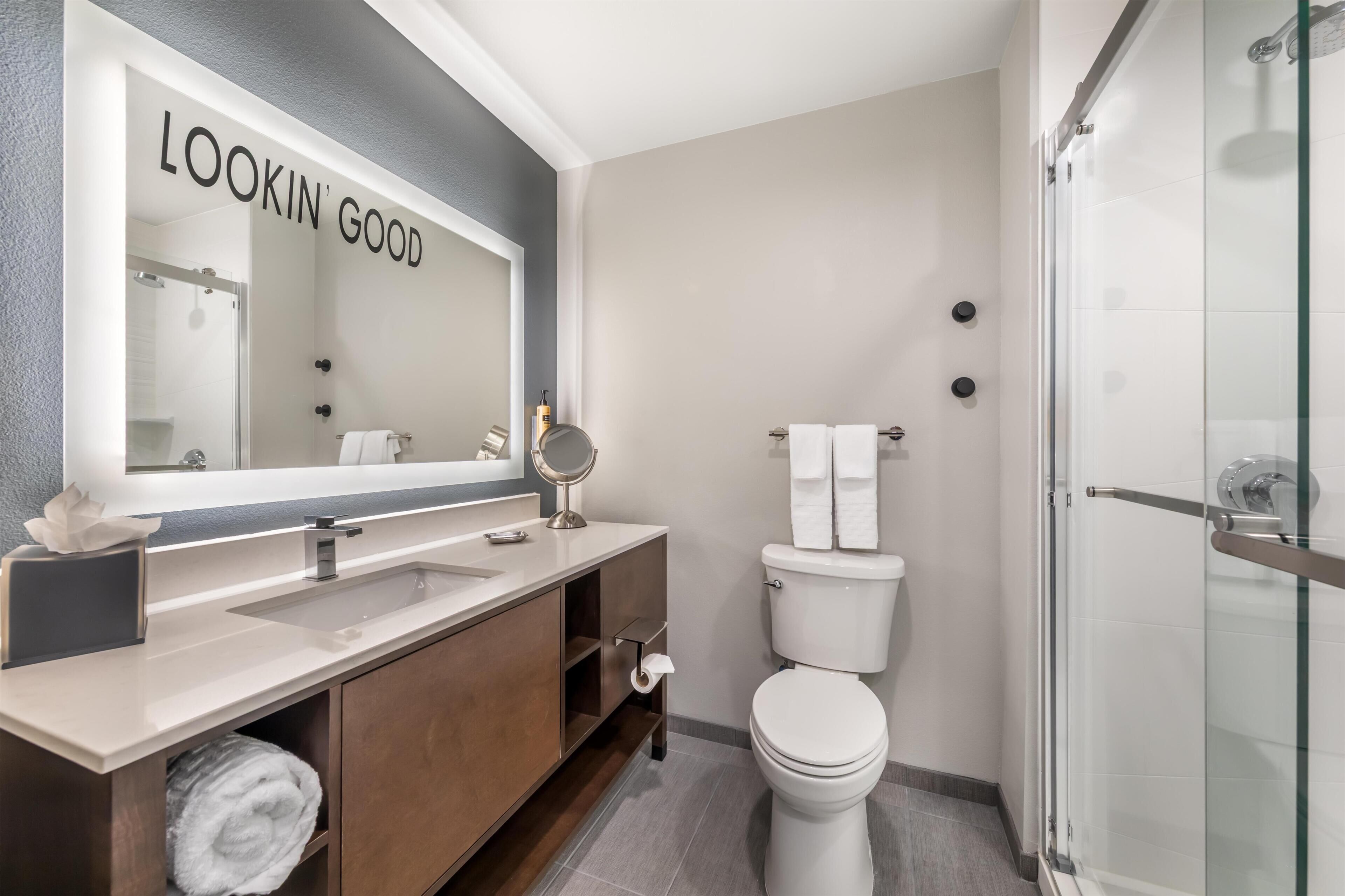 A modern bathroom with a vanity, sink, mirror, toilet, and glass shower enclosure.