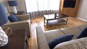 Een woonkamer met een bank, een salontafel, een lamp en een kast.
