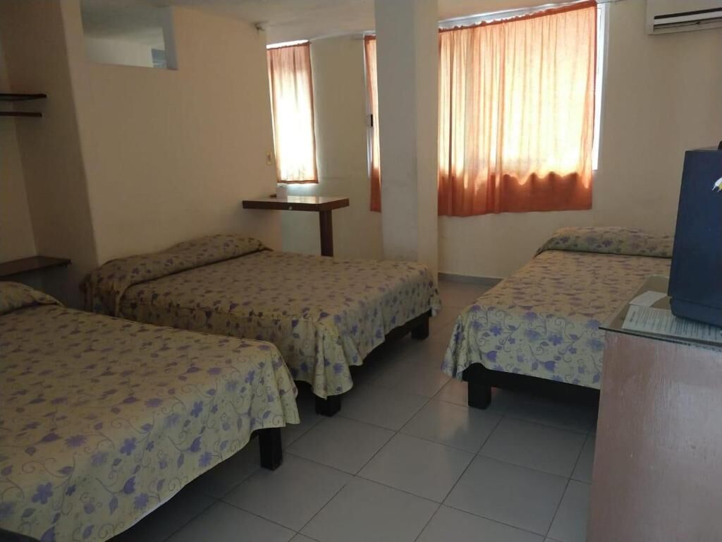 A room with four beds, a desk, and a television.
