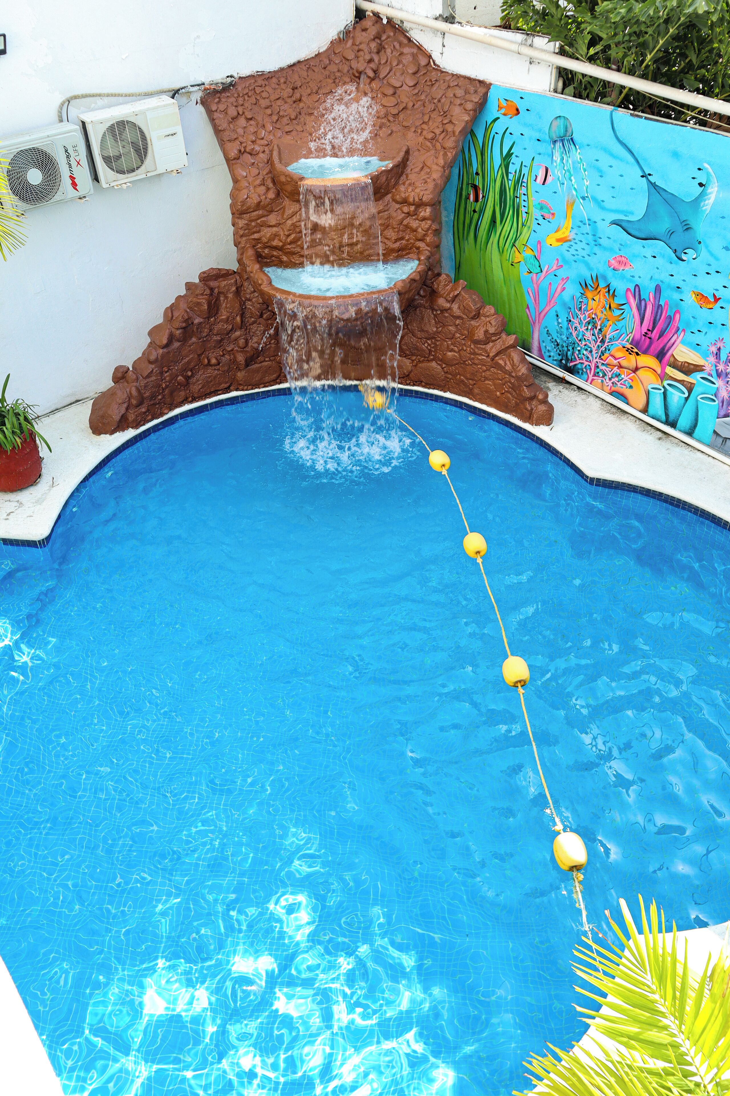 A swimming pool with a waterfall feature and a mural of marine life.