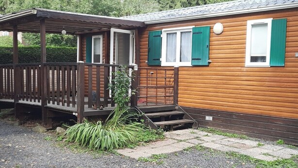 En stuga av trä med en veranda, en liten trappa och en grusgång.
