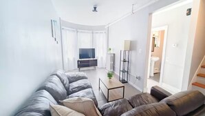 A modern living room with a leather sofa, a flat-screen TV, and a small table with a plant.