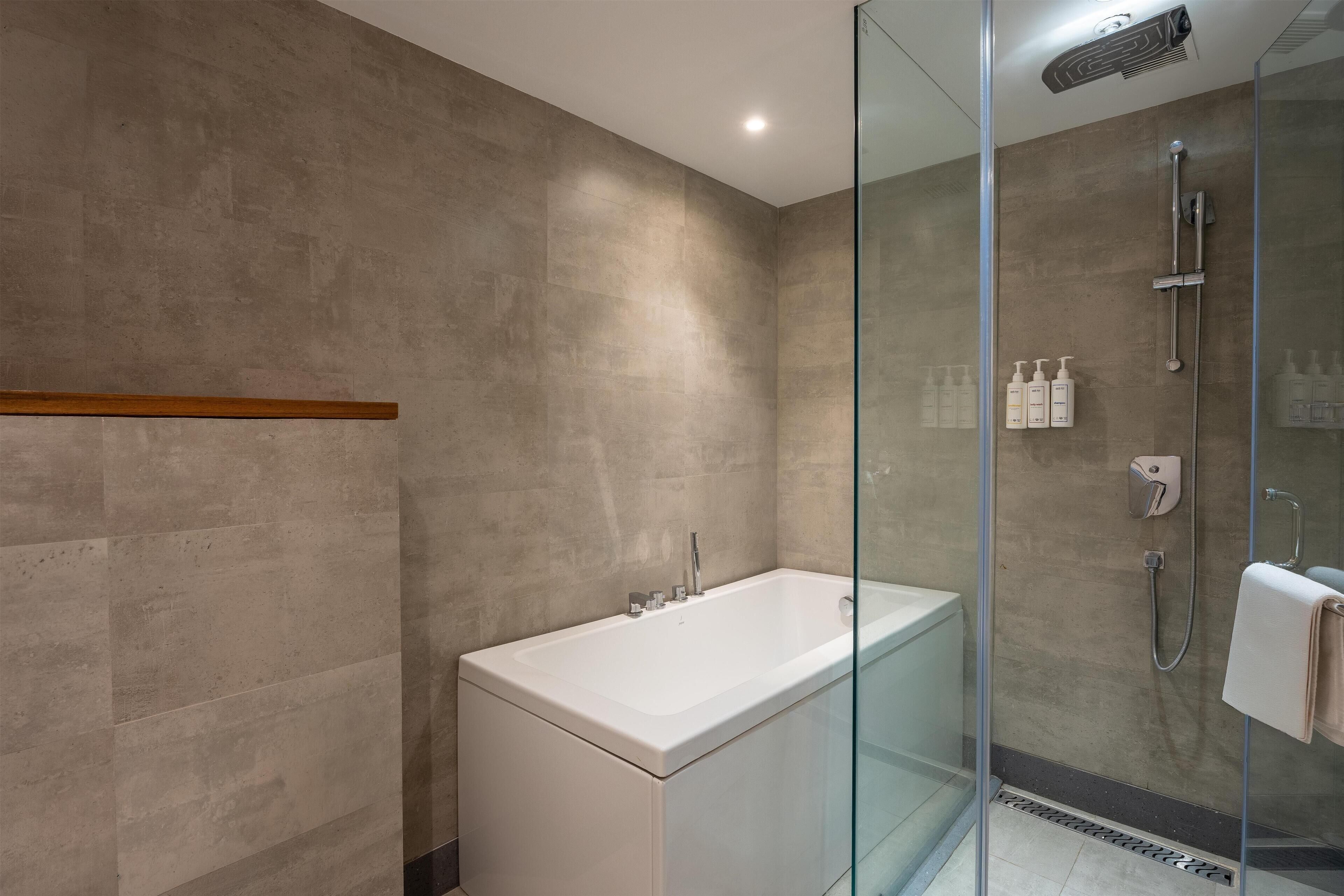 A modern bathroom with a glass-enclosed shower, a standalone bathtub, and a wall-mounted vanity.