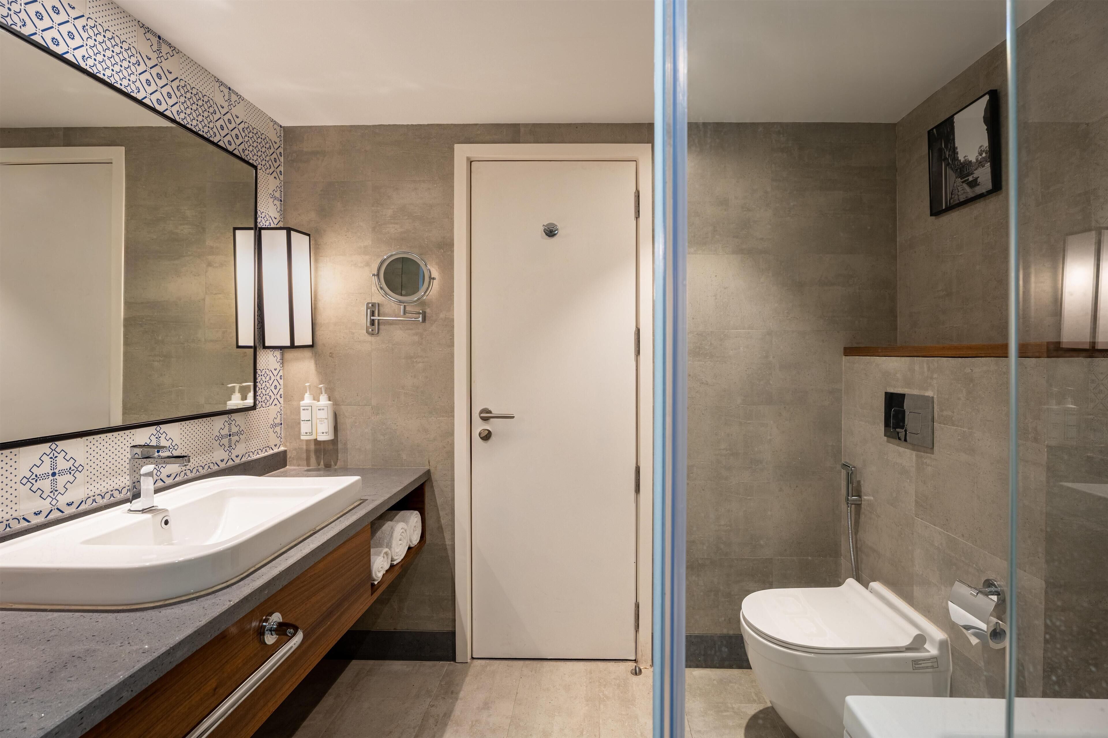 Un baño moderno con dos lavamanos, un espejo, un inodoro y una ducha.