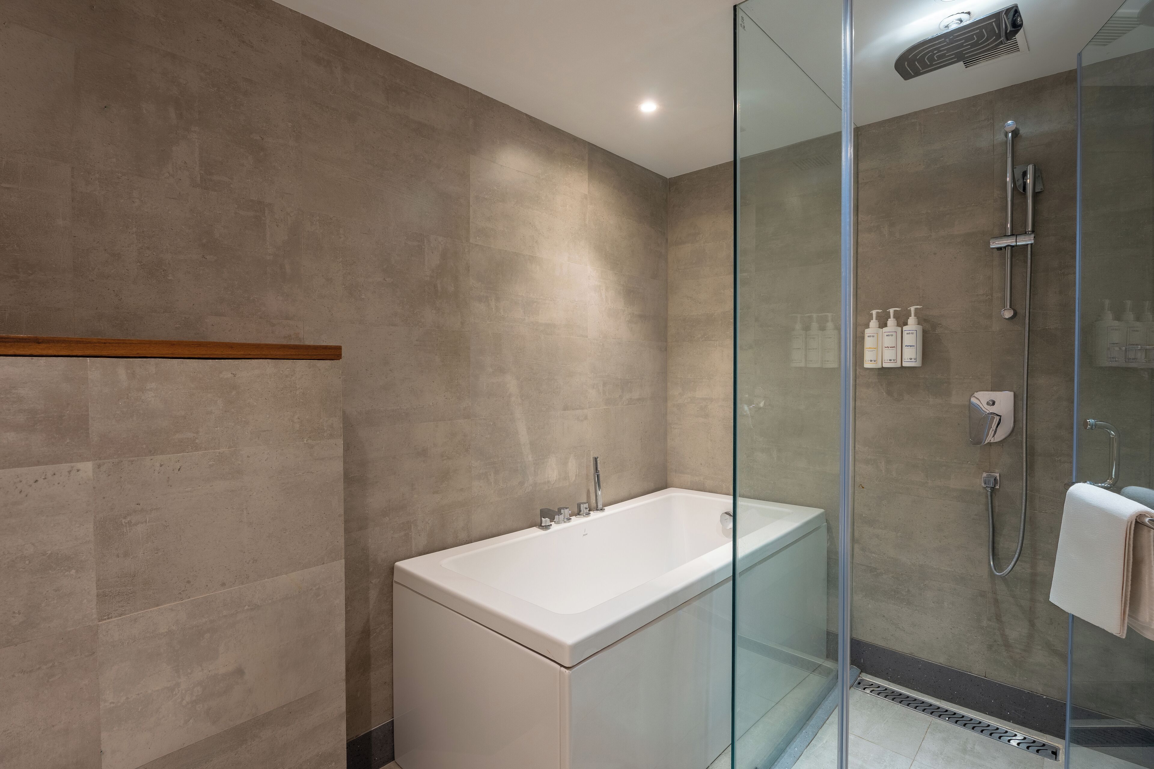 A modern bathroom with a glass-enclosed shower, a standalone bathtub, and a wall-mounted shelf with toiletries.