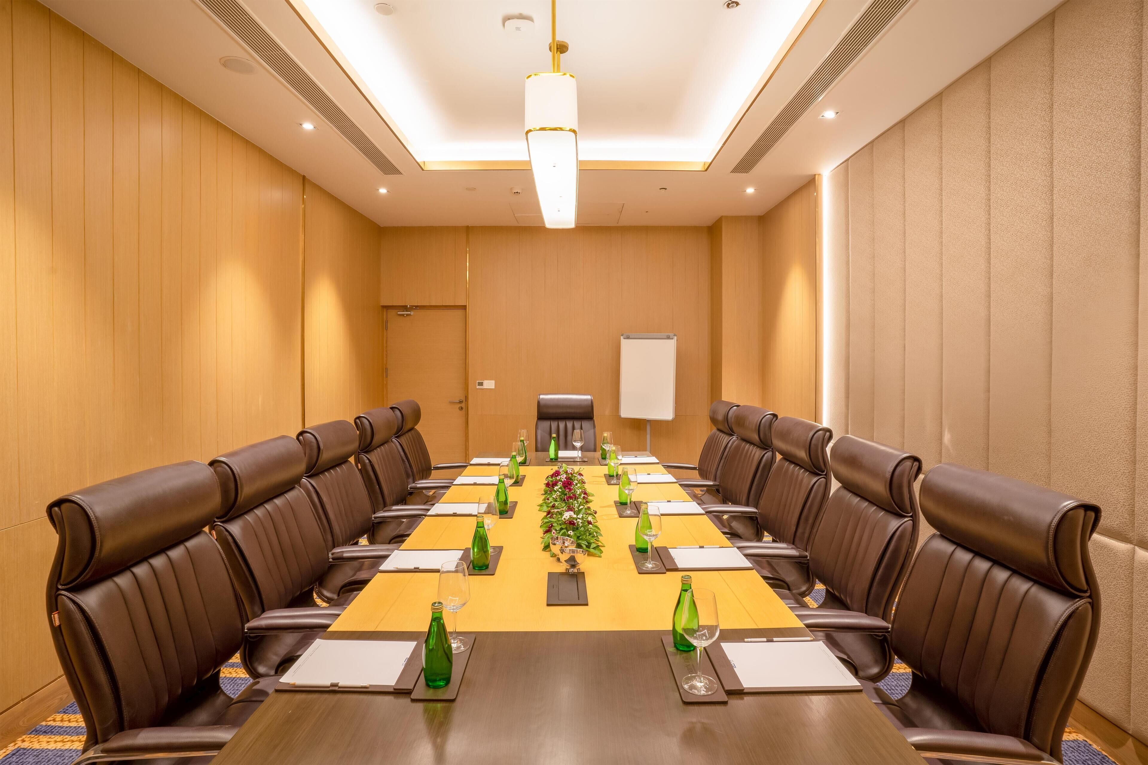 A conference room with a long table, brown leather chairs, and a whiteboard.