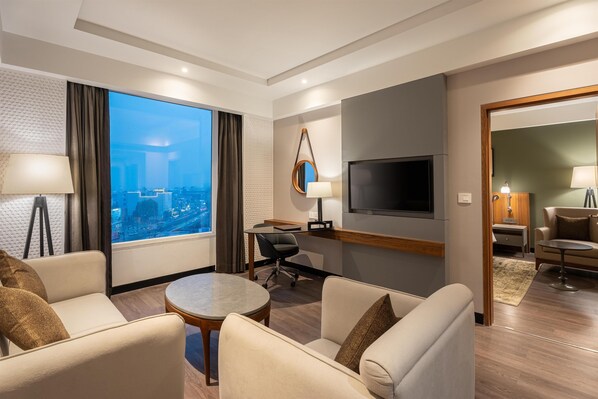 A modern hotel room with a city view, a flat-screen TV, a dining area, and a cozy seating space. - Park Inn By Radisson Lucknow Vikas Nagar (Lucknow)