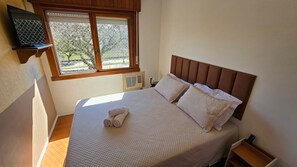 A bedroom with a bed, a window, and a bedside table. - Estadia Tri Ótima Localização e Garagem (Porto Alegre)