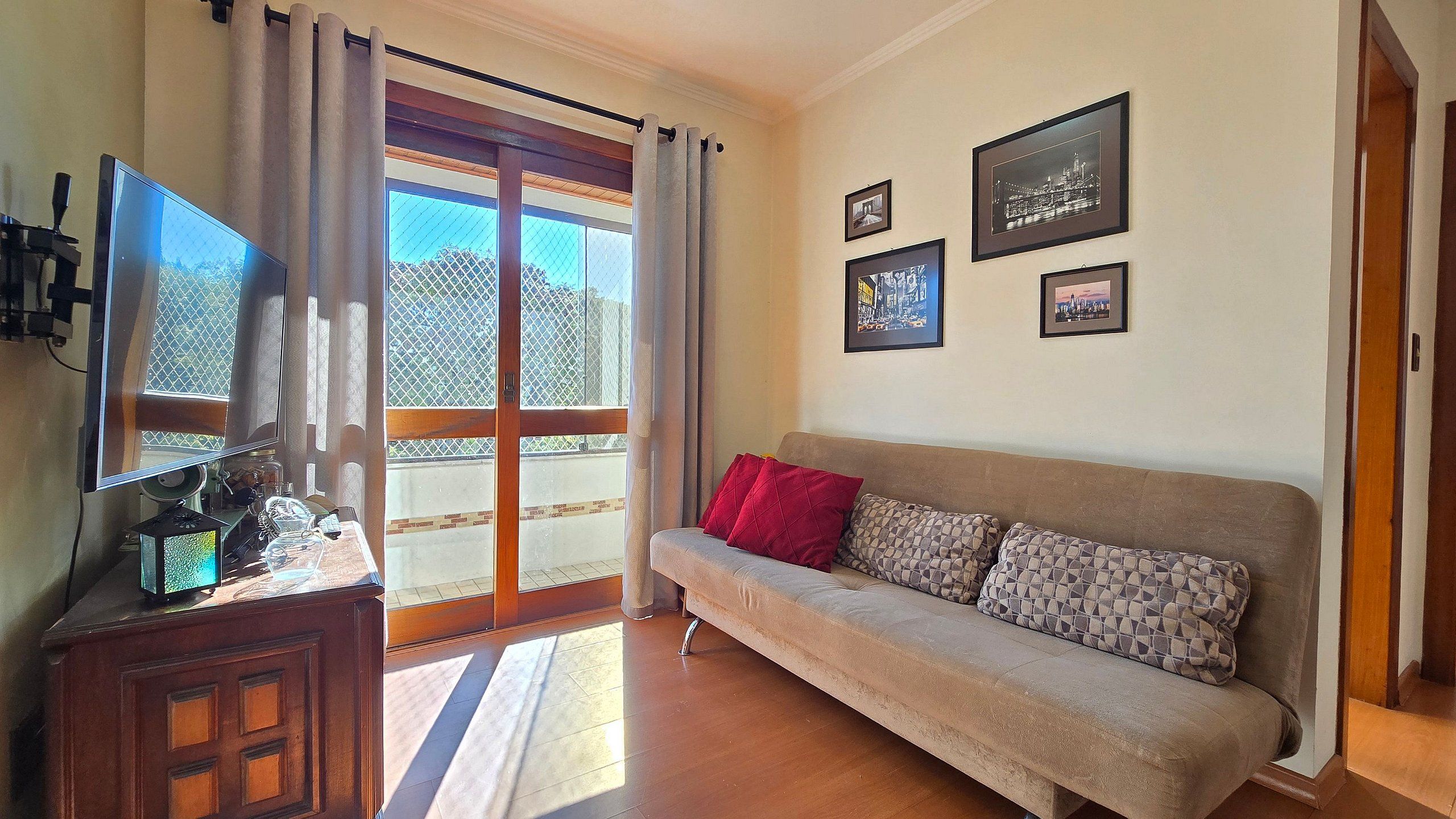 A living room with a sofa, a television, and a window with curtains.