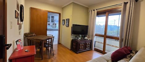 Una sala de estar con un sofá, un televisor y un comedor con una mesa y sillas.