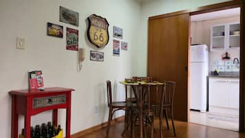 Un comedor con una mesa y sillas de madera, un armario rojo con botellas y una pared decorada con carteles antiguos de coches y servicio de taller.