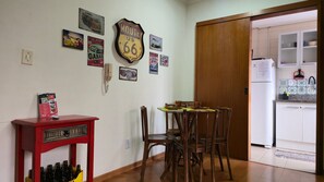 Un comedor con una mesa y sillas de madera, un armario rojo con botellas y una pared decorada con carteles antiguos de coches y servicio de taller.