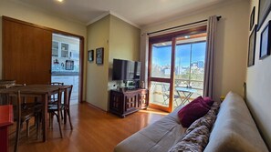 Una sala de estar con un sofá, una televisión y un comedor con una mesa y sillas.
