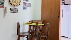 A dining area with a table and chairs, a refrigerator, and wall decorations including a Route 66 sign. - Estadia Tri Ótima Localização e Garagem (Porto Alegre)