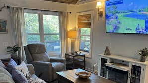 A cozy living room with a fireplace, comfortable seating, and a television displaying a golf match.