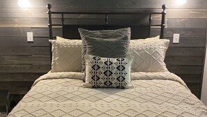 A bed with a quilted bedspread, two pillows, and a wall-mounted skull decoration.