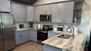 A modern kitchen with light gray cabinets, stainless steel appliances, and a marble countertop.