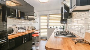 A modern kitchen with black cabinets, a wooden countertop, a gas stove, a microwave, and a clock on the wall. - Esplanade Gardens, Apartment 1 (Scarborough)
