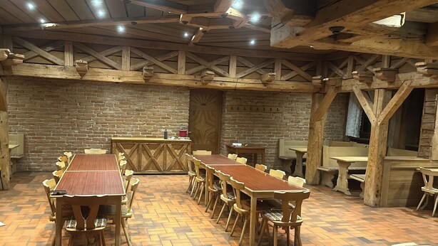 A rustic dining area with wooden tables and chairs, a brick wall, and exposed wooden beams on the ceiling. - Hotel Restaurant Ampertal (Haag an der Amper)