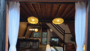 Un interior acogedor con techo de madera, un comedor y una sala de estar con sofá y cortinas.