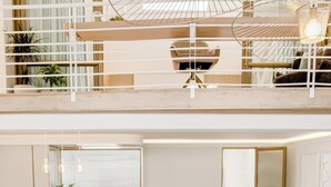 Un espace de vie moderne, aménagé sur plusieurs niveaux, comprenant un grand canapé d’angle, un coin repas et une cuisine.