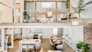 Un intérieur moderne comprenant un coin repas, une cuisine et un balcon agrémenté d’un luminaire suspendu original.